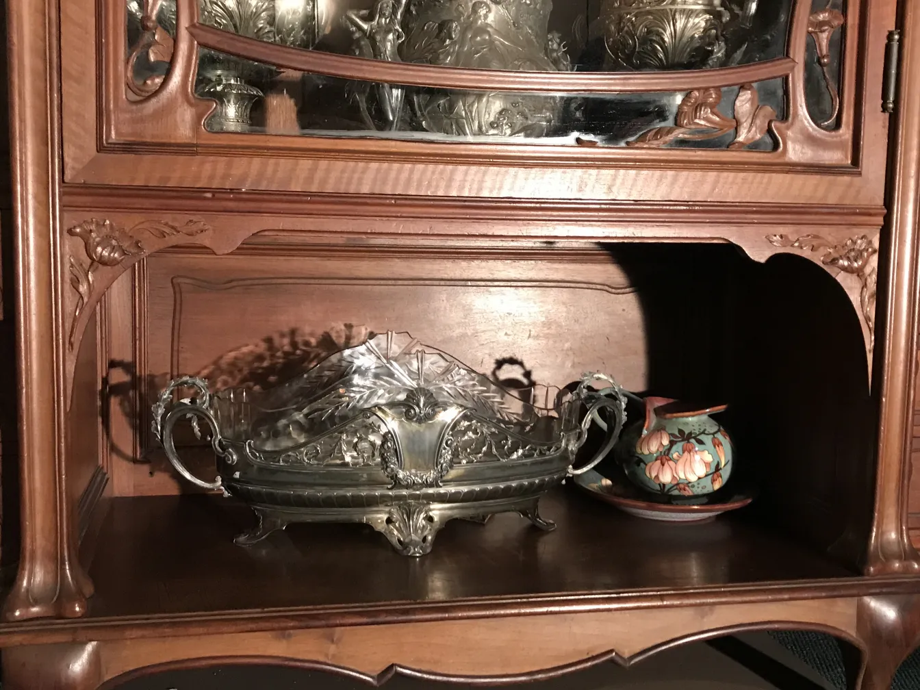 Vitrina antigua con detalles finos y espejos. Ambiente elegante con otros objetos decorativos.