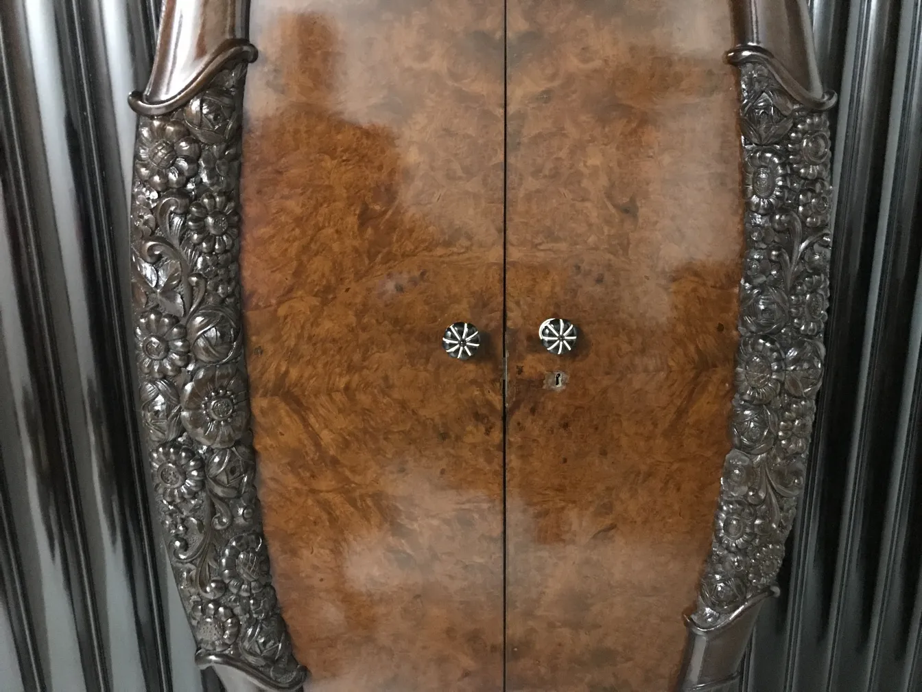 Vitrine antiga de madeira com detalhes entalhados e acabamentos decorativos.