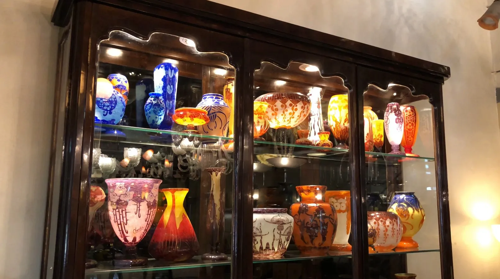 Vitrine antiga exibindo vasos coloridos