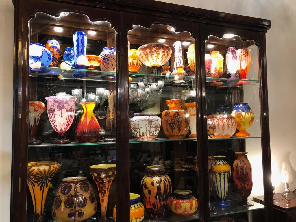 Vitrine ancienne éclairée avec des vases colorés et des bocaux