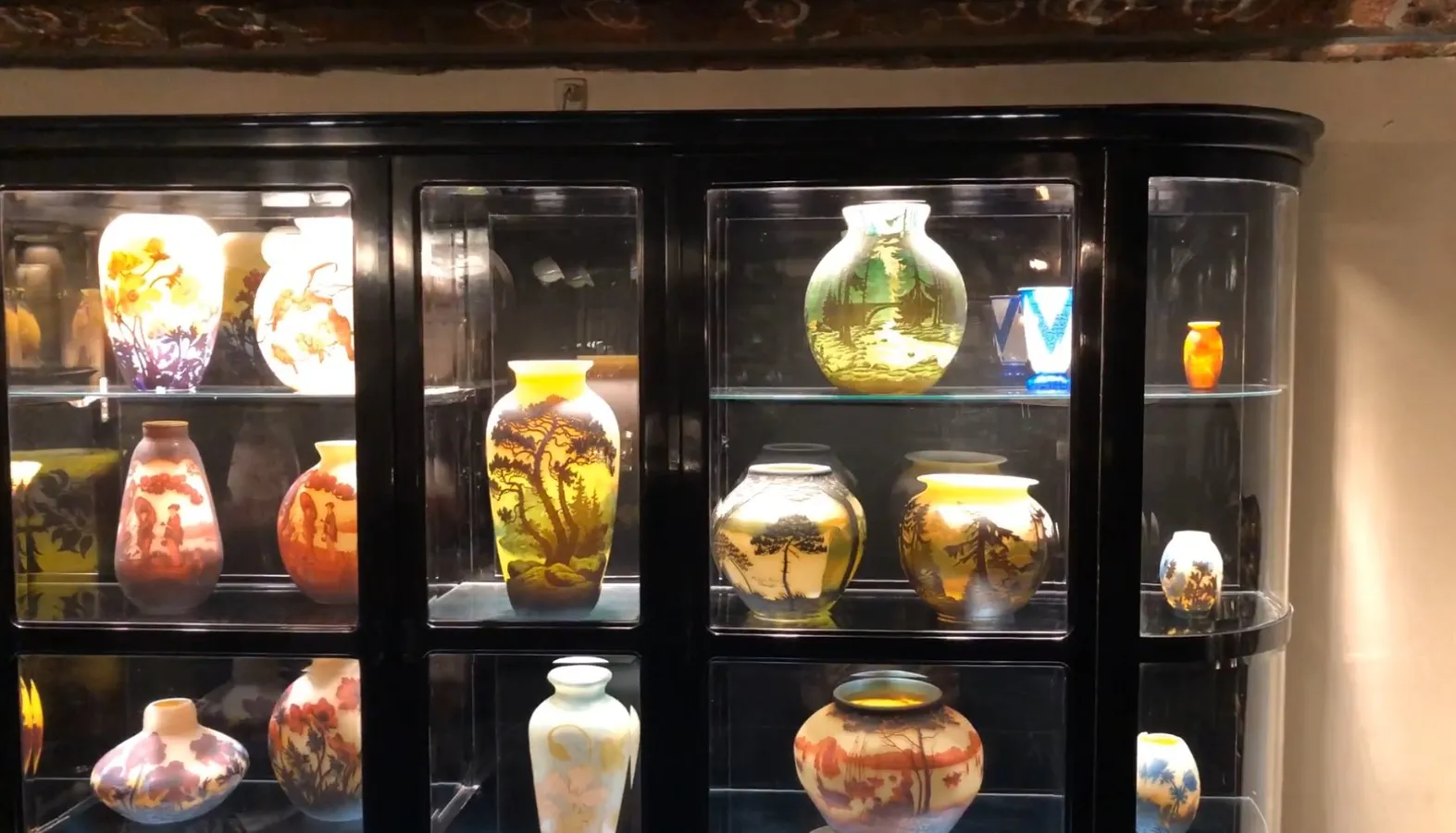 Vitrina antigua con varios jarrones coloridos en su interior