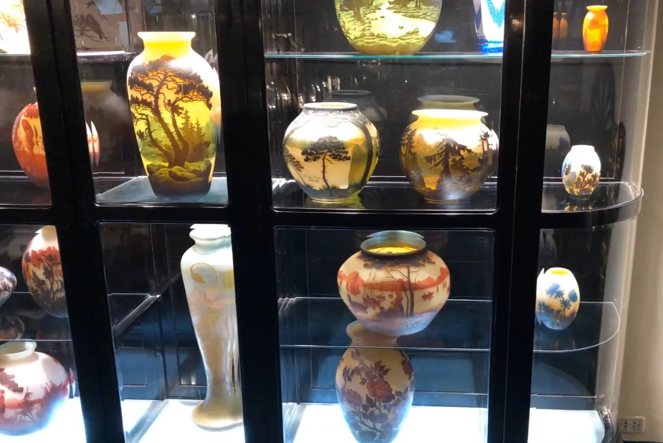 antique display cabinet showcasing various decorative vases