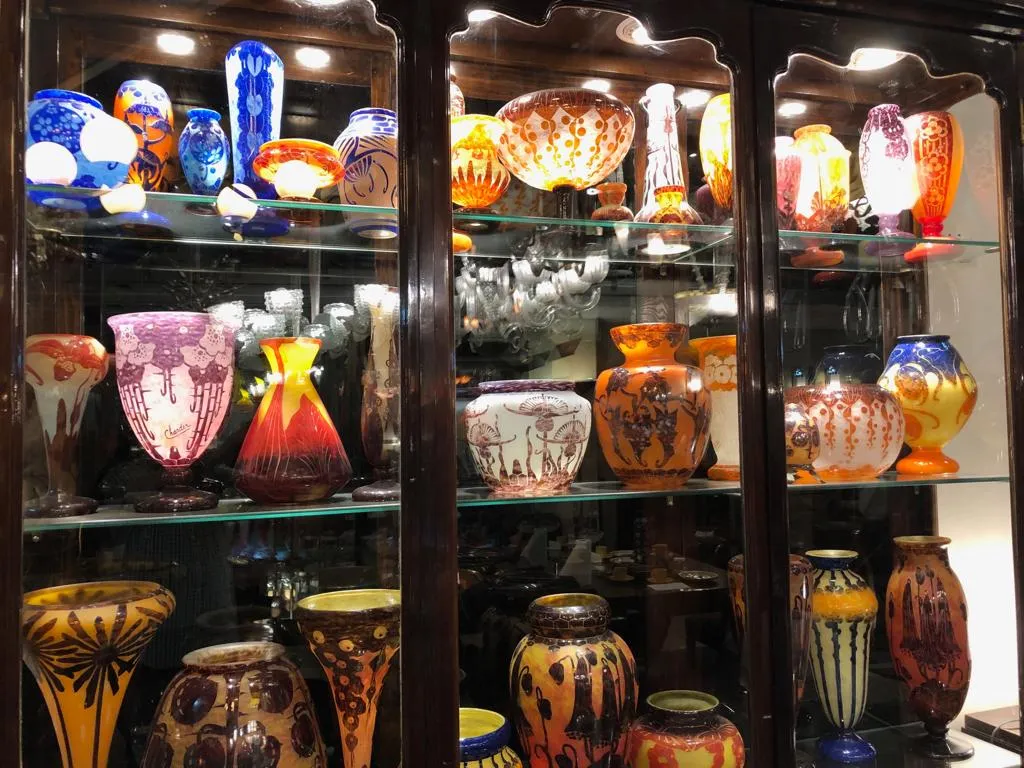 Vitrina antigua con diversos jarrones decorativos de colores vibrantes en un ambiente acogedor.