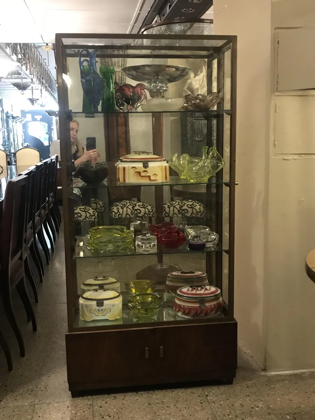 Vitrina antigua con varios objetos de exhibición, incluyendo colores vibrantes y una forma elegante en un entorno clásico