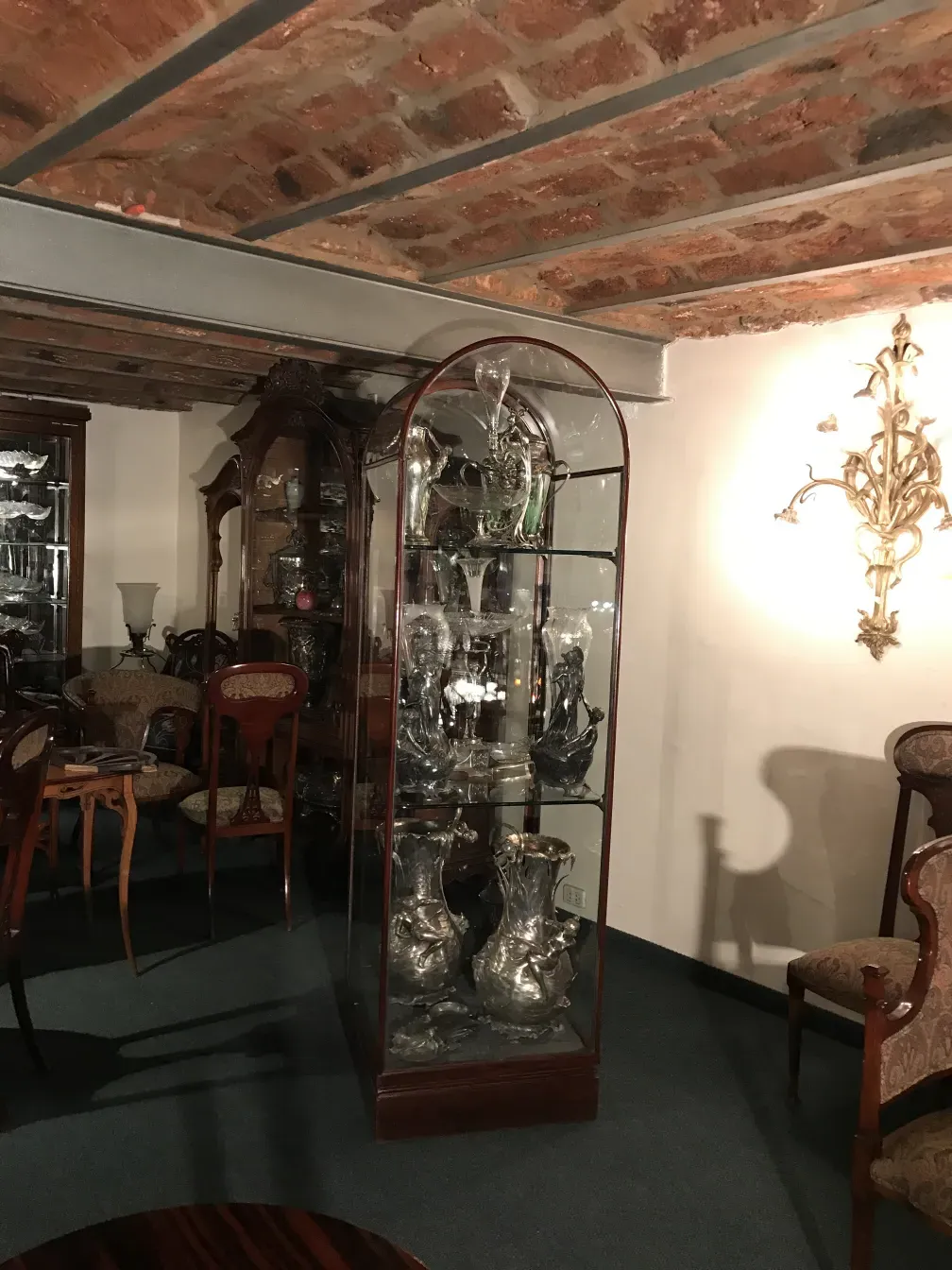 Vitrine antiga exibindo objetos decorativos sob luzes brilhantes.