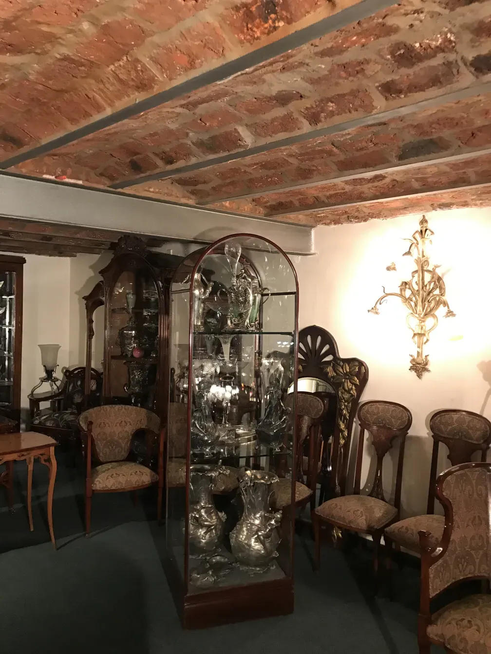 Antique display cabinet with decorative collectibles, vintage furniture in background.