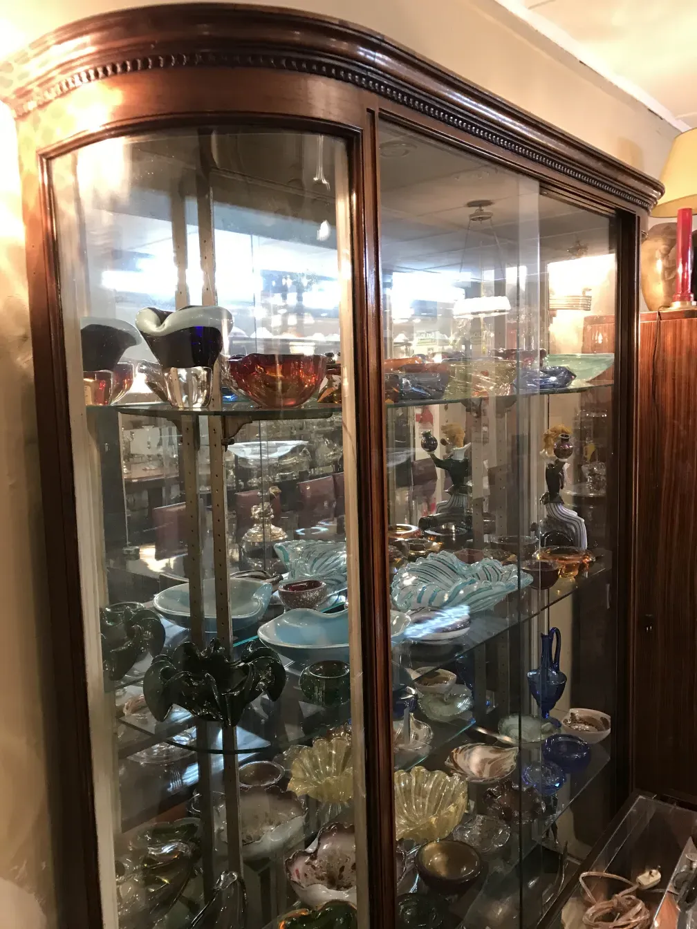 Vitrine antiga com diversos objetos decorativos de vidro.