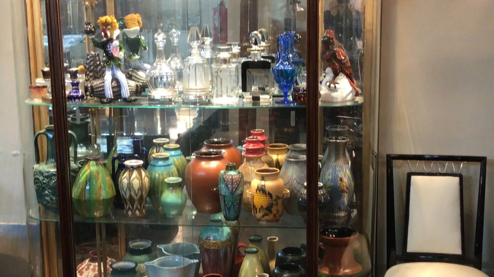 Vitrine ancienne présentant divers objets décoratifs colorés.