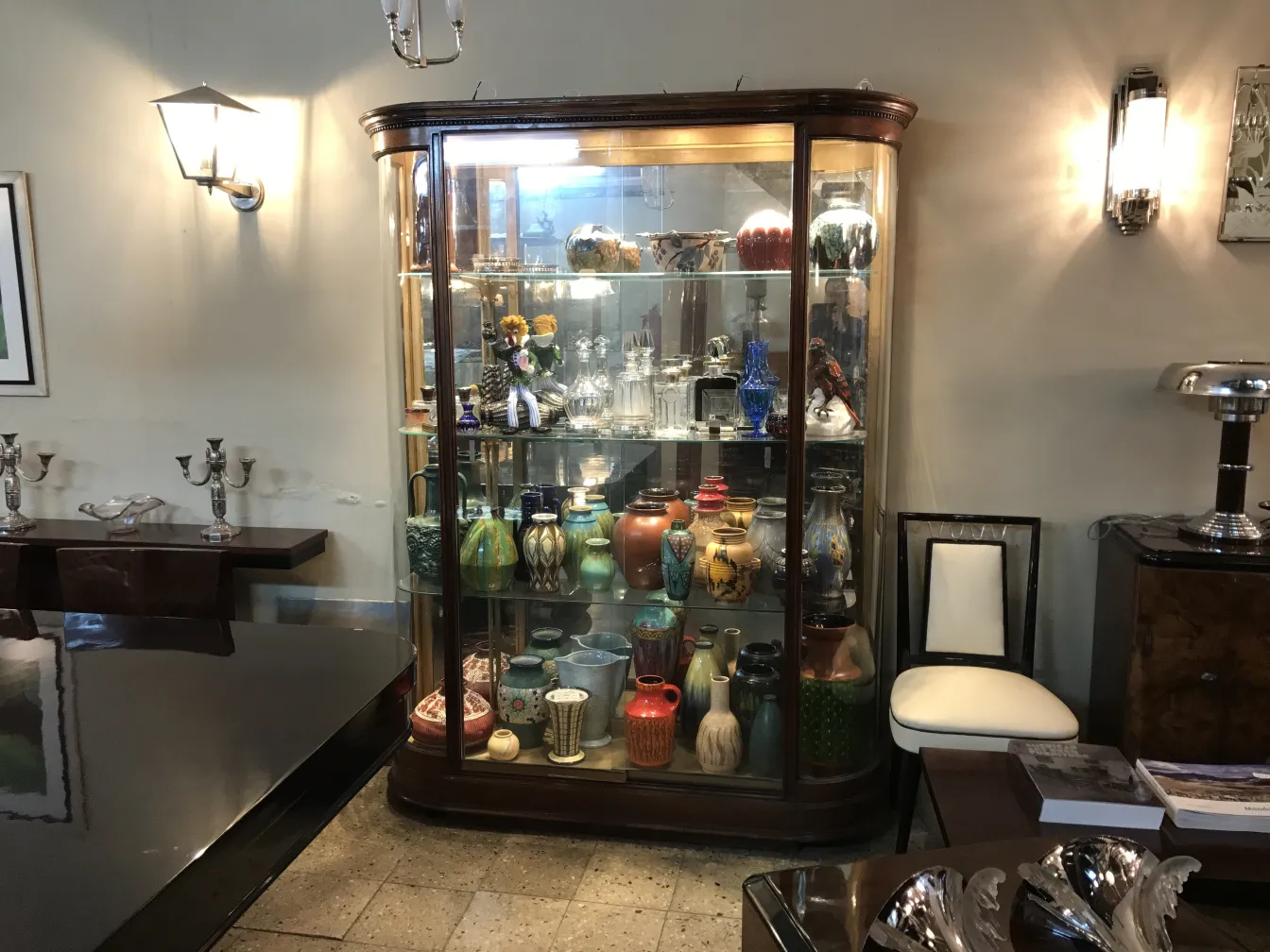 Vitrine ancienne avec divers objets décoratifs et céramiques colorées, dans un cadre élégant.