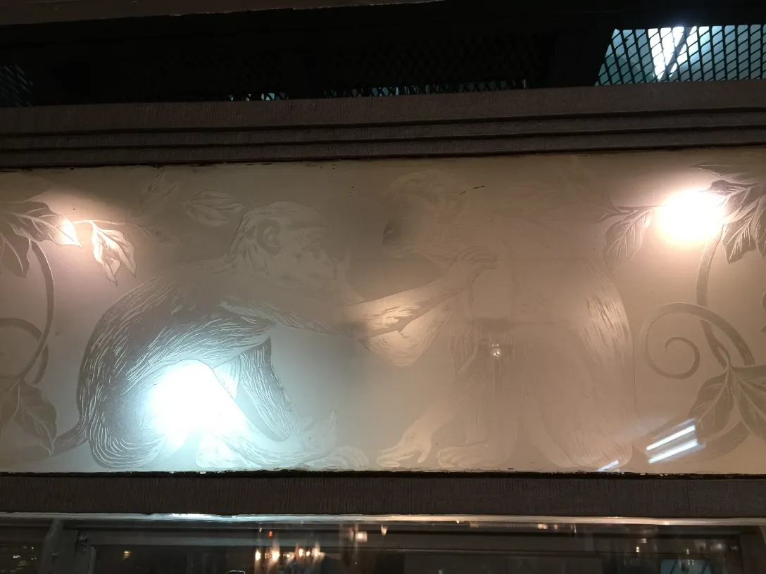 antique display cabinet featuring monkey engravings and floral decorations