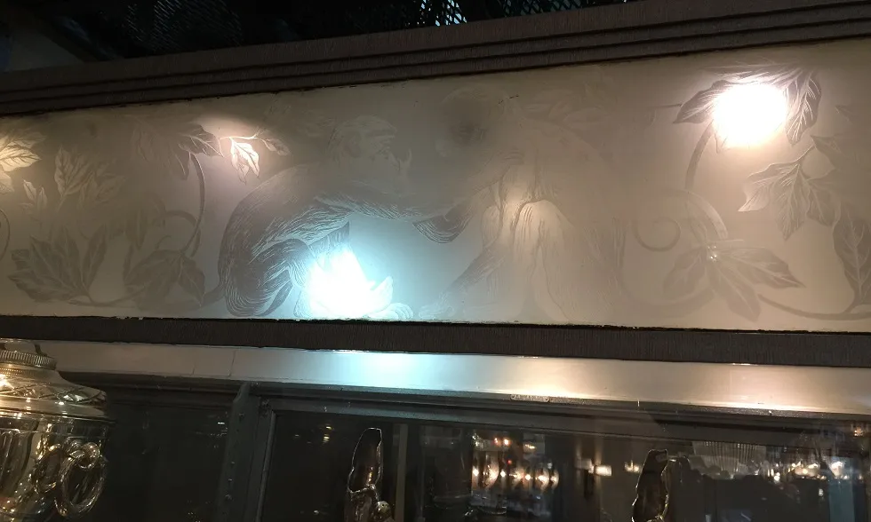 Vitrine antiga com design de macaco e folhas gravadas.