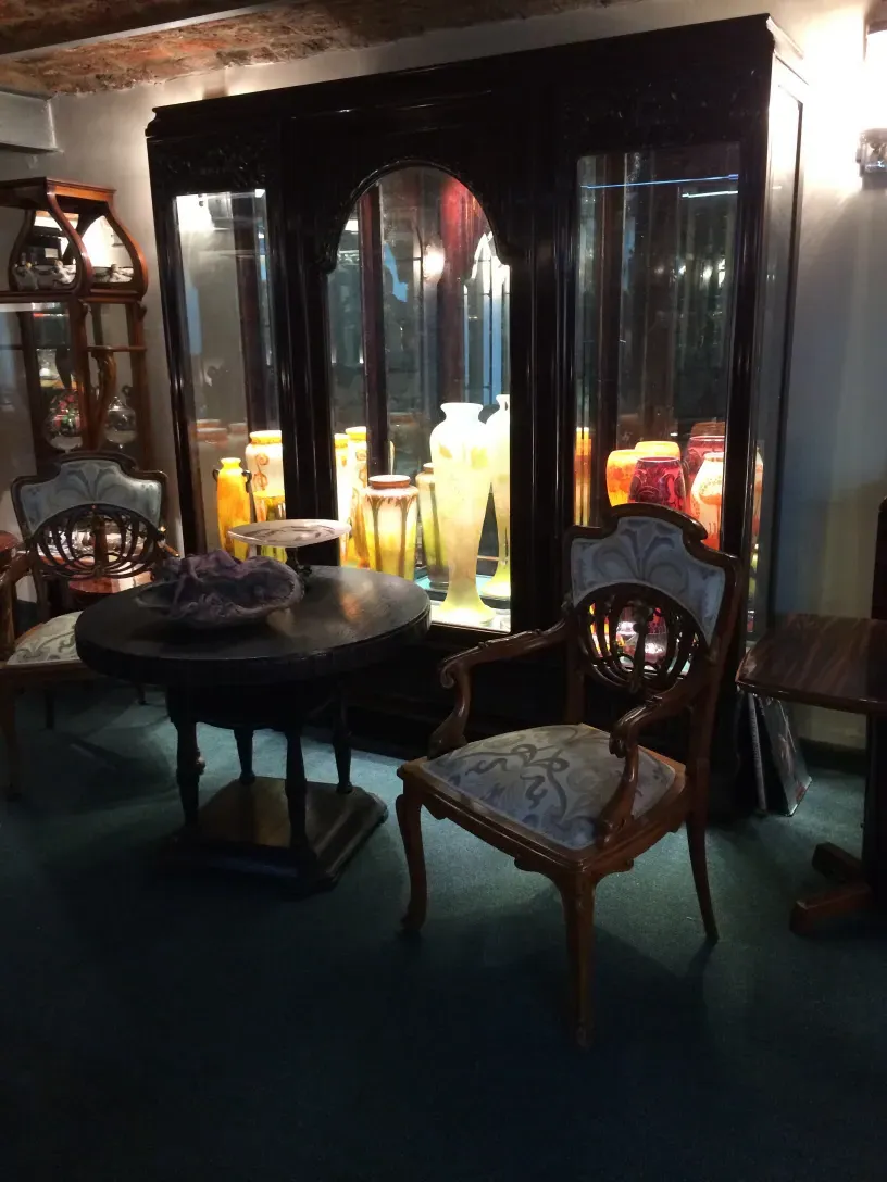 antike vitrine mit eleganter dekoration und stühlen ringsherum