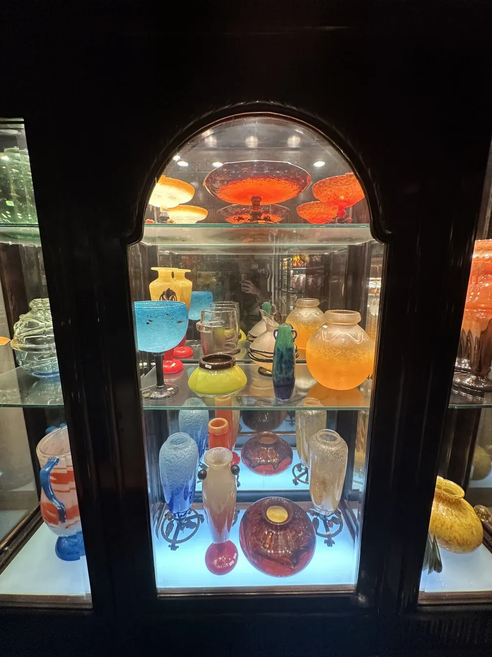 vitrine antique avec des objets décoratifs colorés dans une vitrine éclairée.