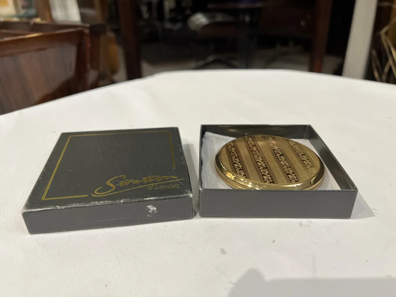 Antique gold compact with elegant design, in its box