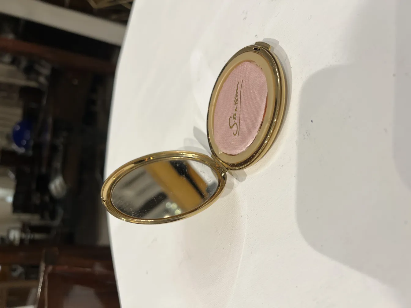 polvera antiga com espelho e blush rosa, ambiente clássico