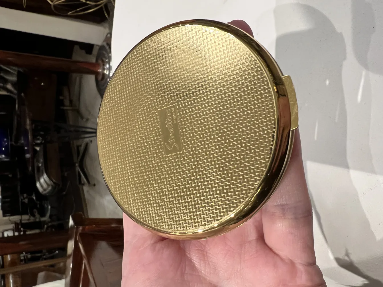 antike goldene polvera mit strukturiertem Design in der Hand