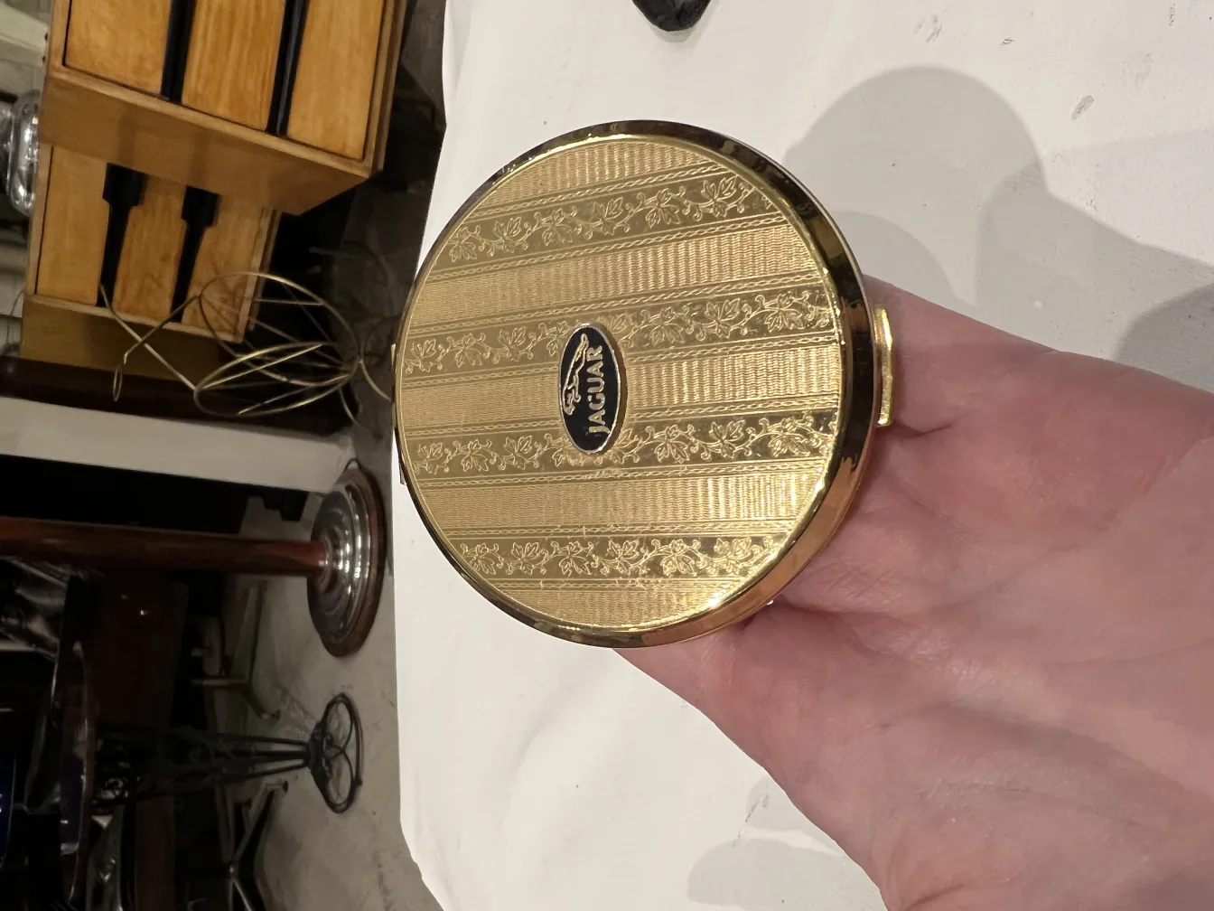 Polvera antica con design dorato ed elegante in una mano.