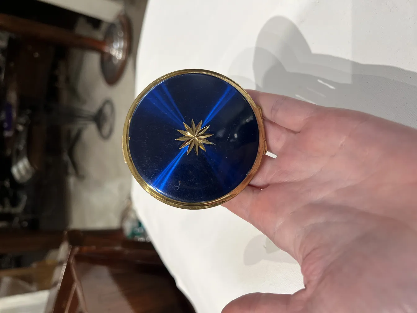 Polvera ancienne avec un magnifique design bleu et doré, tenue dans une main