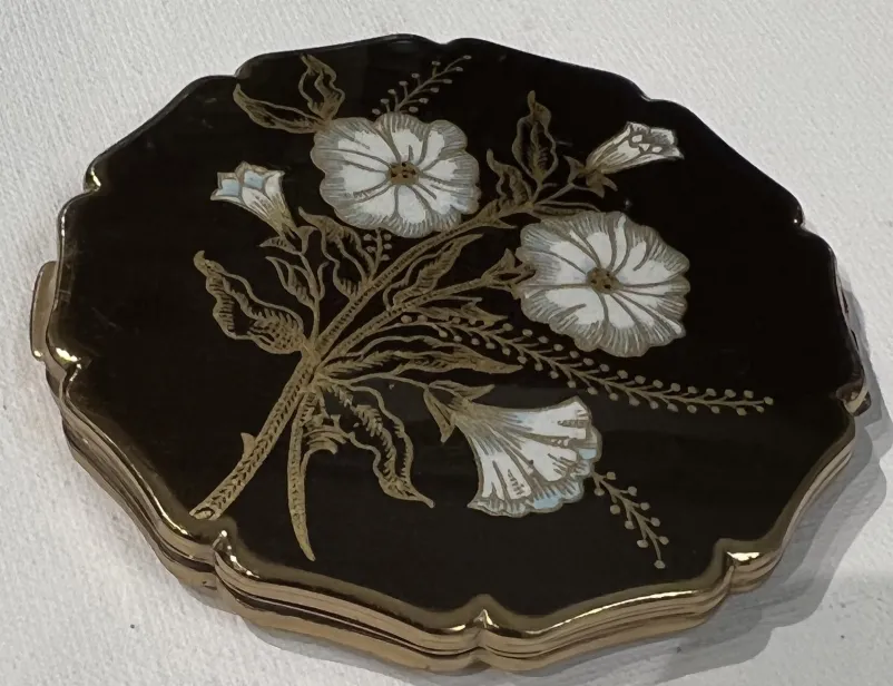 antique compact featuring light-toned flowers on a dark background