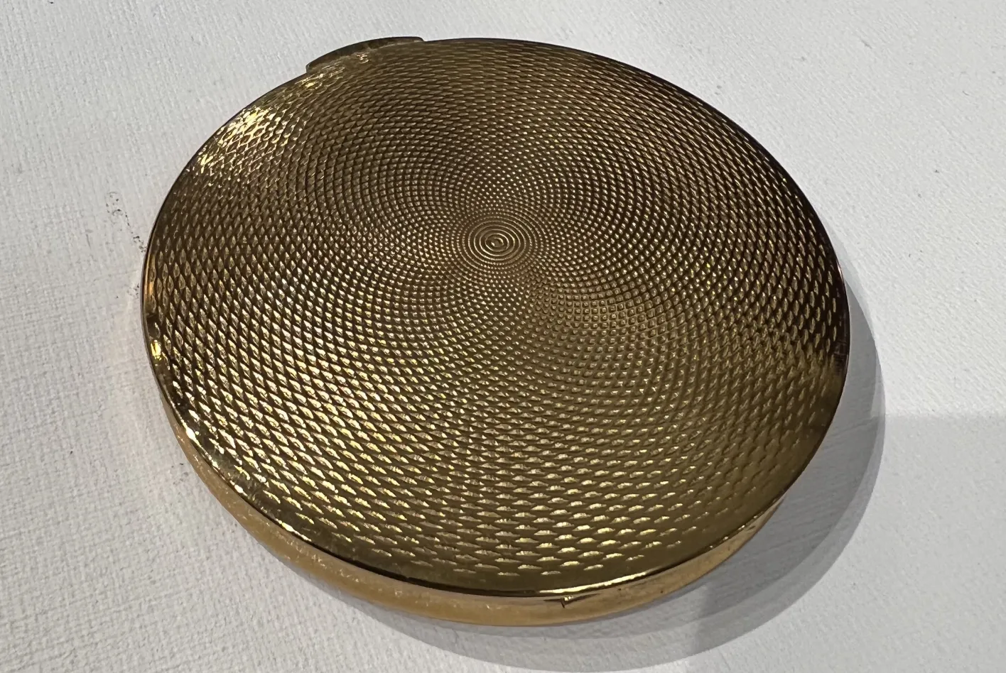 Polvera antigua con detalles de diseño en relieve y con un acabado dorado