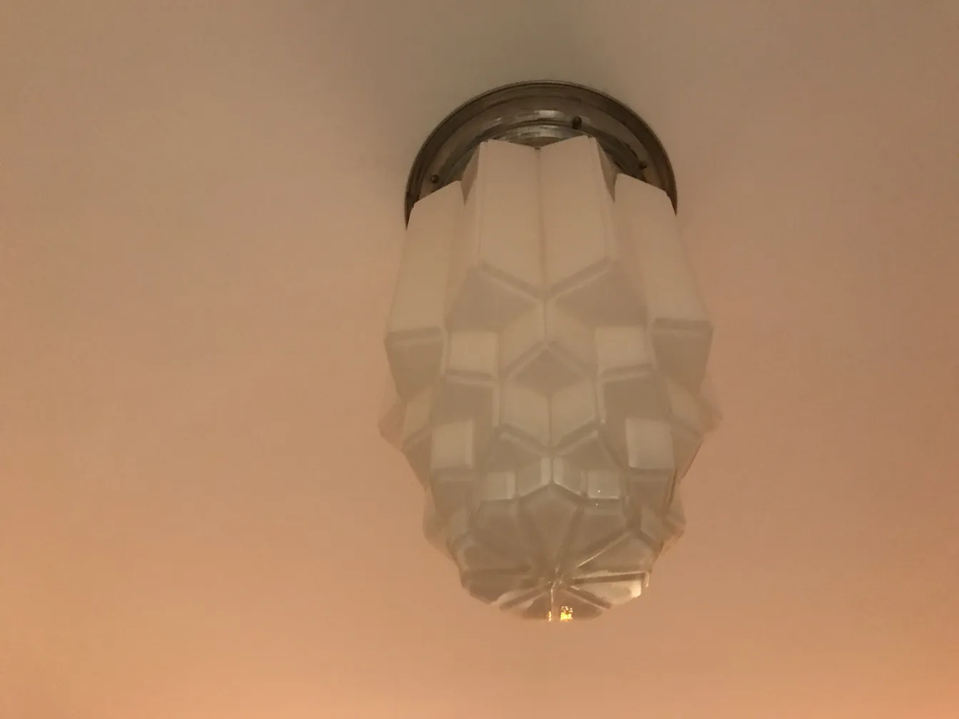 2 antike Deckenleuchten mit geometrischen Formen in einem beleuchteten Raum