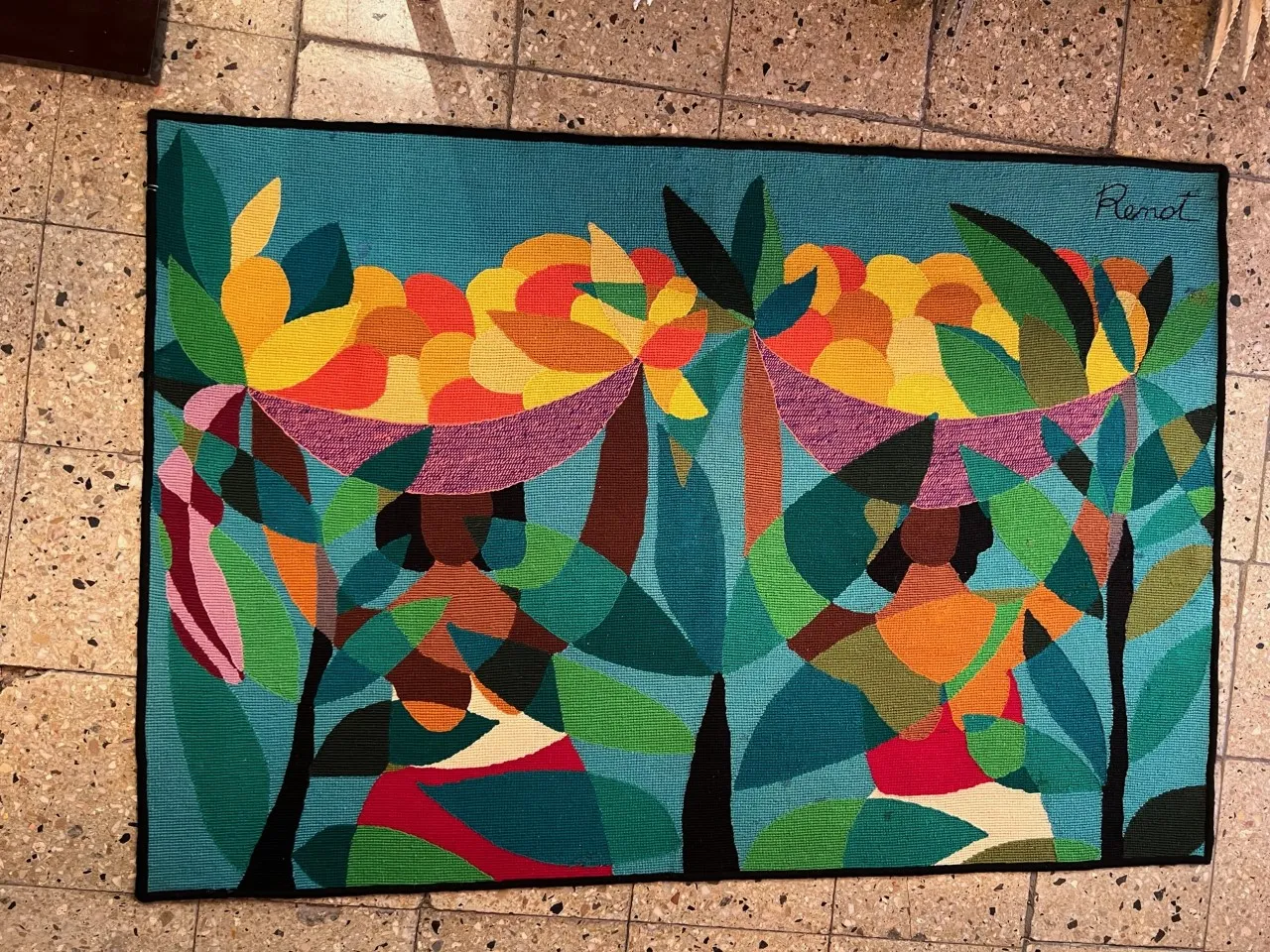 tapisserie ancienne avec des couleurs vives et des formes géométriques dans un cadre neutre