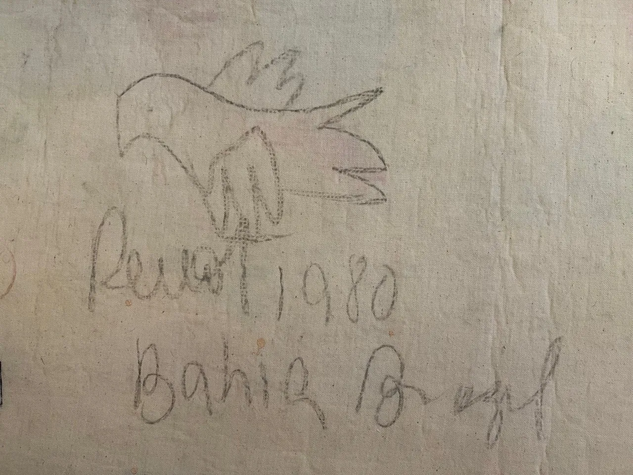 Arazzo antico con design di uccello in colori tenui e sfondo chiaro, che mostra dettagli di cucitura.