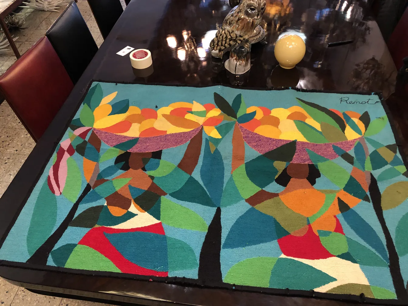 Tapisserie ancienne représentant des fruits colorés et des feuilles sur un fond bleu.