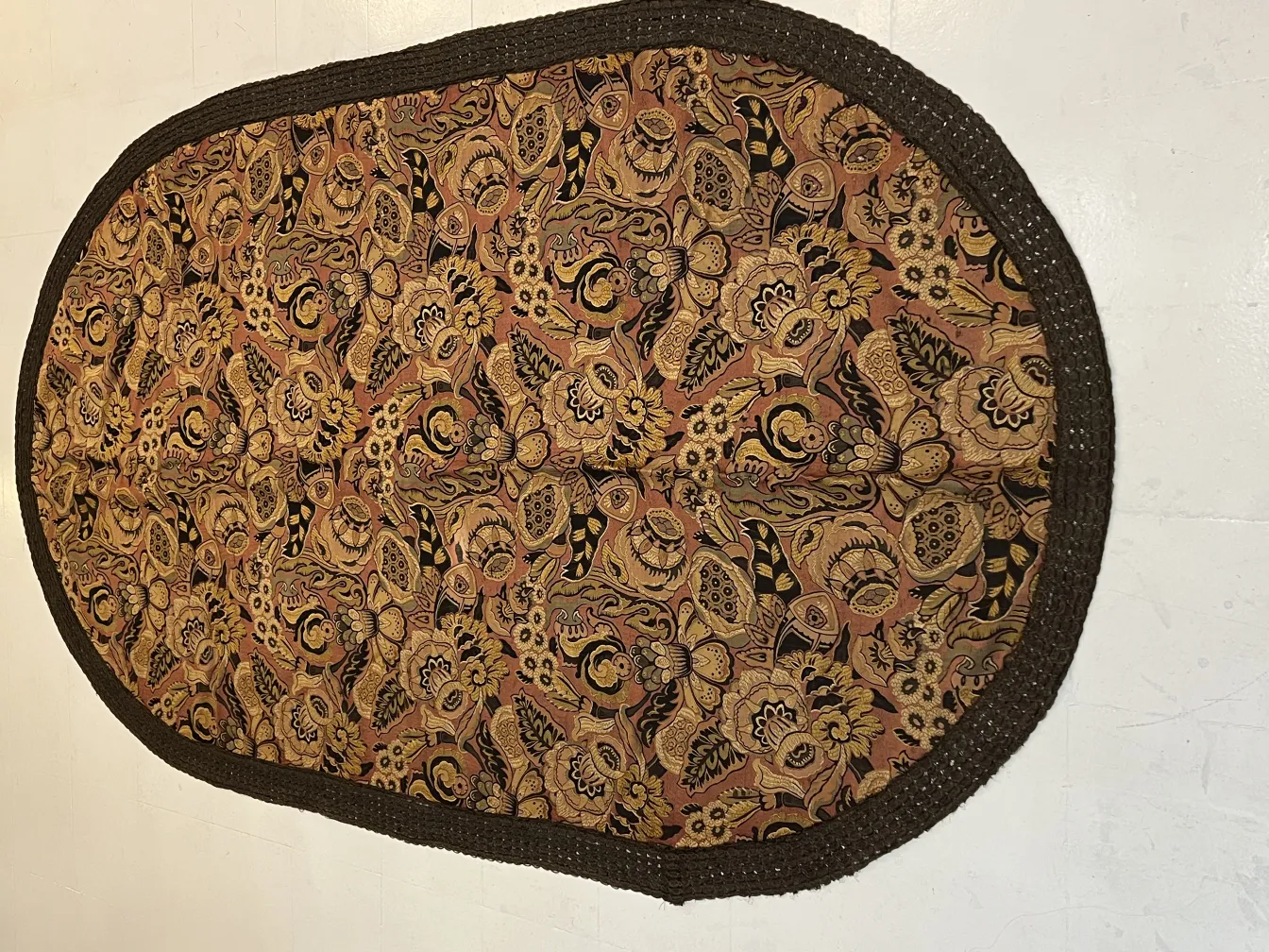 nappe ovale ancienne avec des motifs floraux colorés sur fond marron