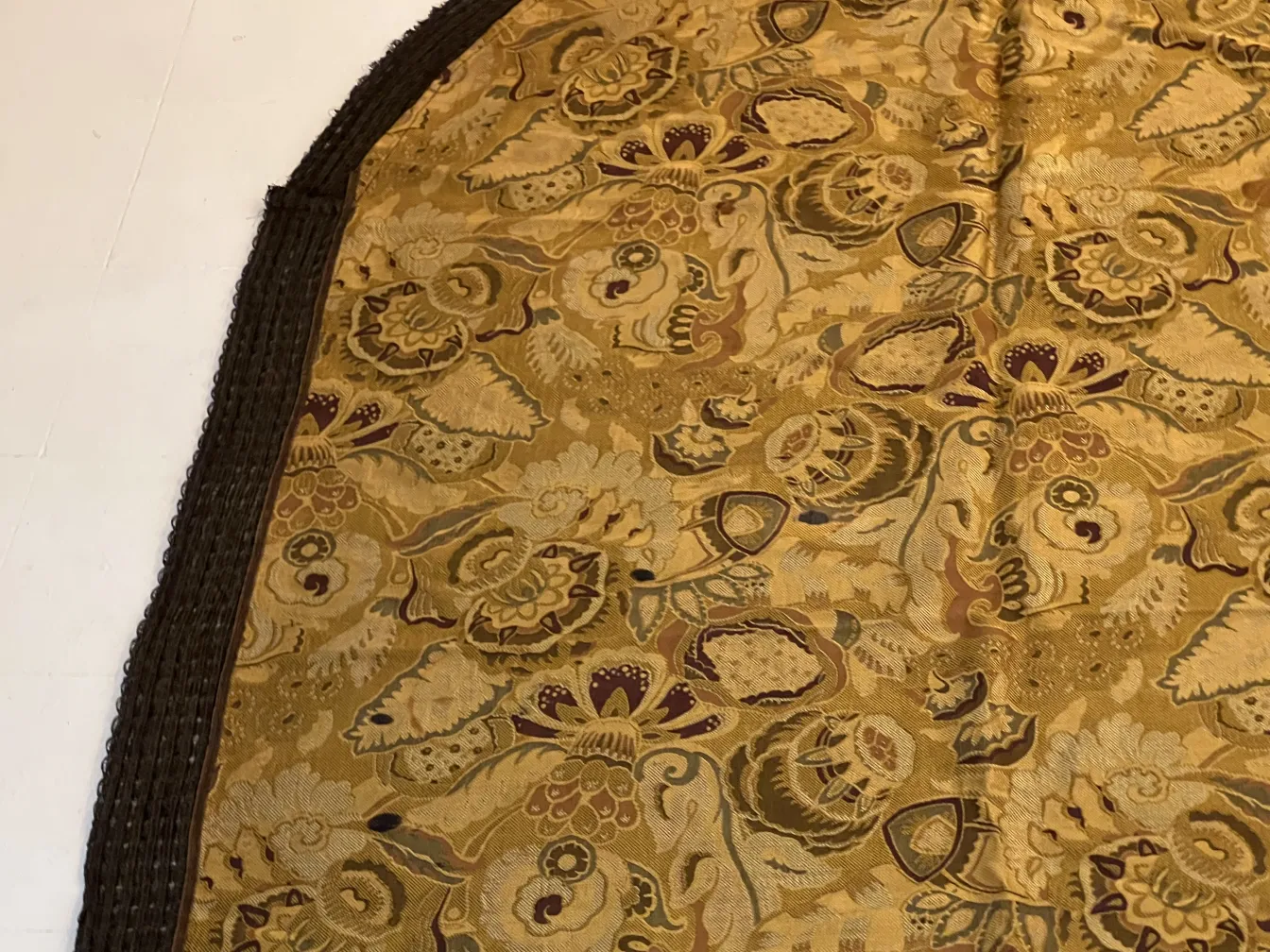 प्राचीन मेज़पोश जो सुनहरे रंगों में फूलों से बना है