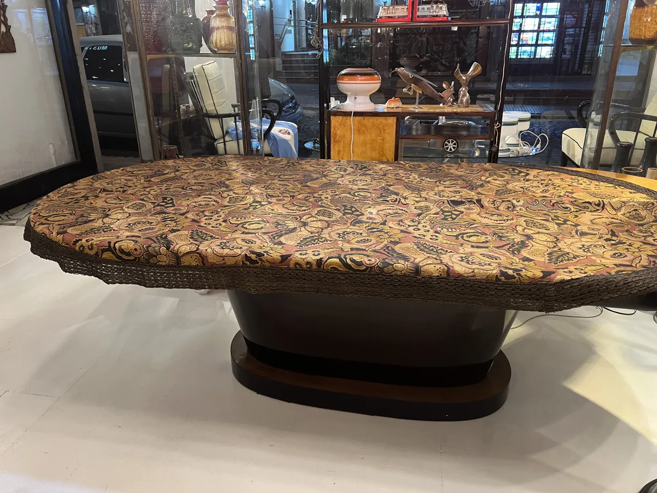 toalha de mesa antiga sobre mesa oval, com padrões coloridos e bordas decorativas