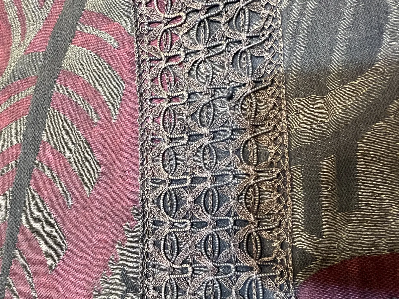 dettaglio di tovaglia antica con bordi decorativi, sfondo colorato