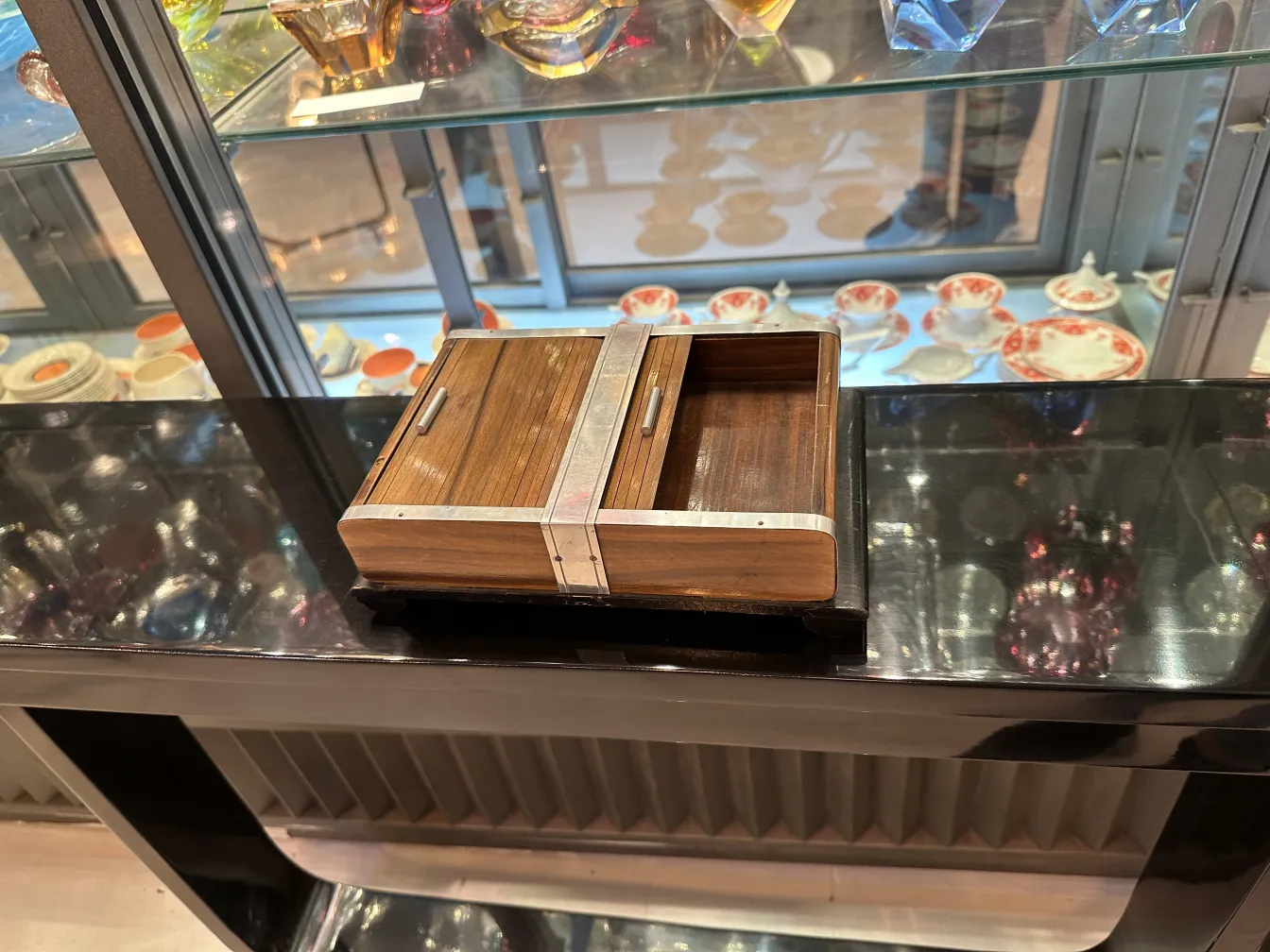 Antique jewelry box with metal accents and interior compartments, displayed on a dark shelf.