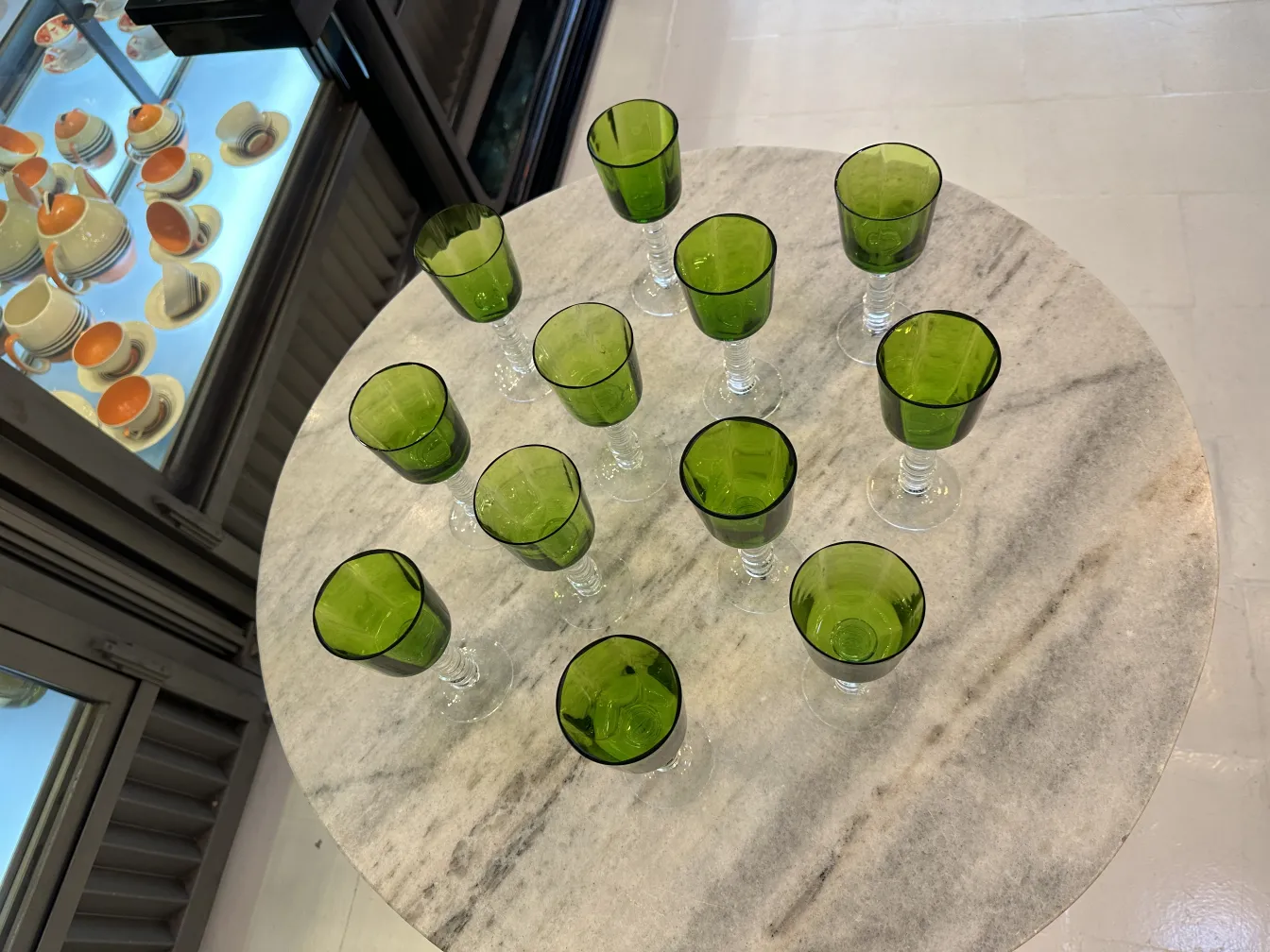 Set of 12 antique green glasses on a marble table