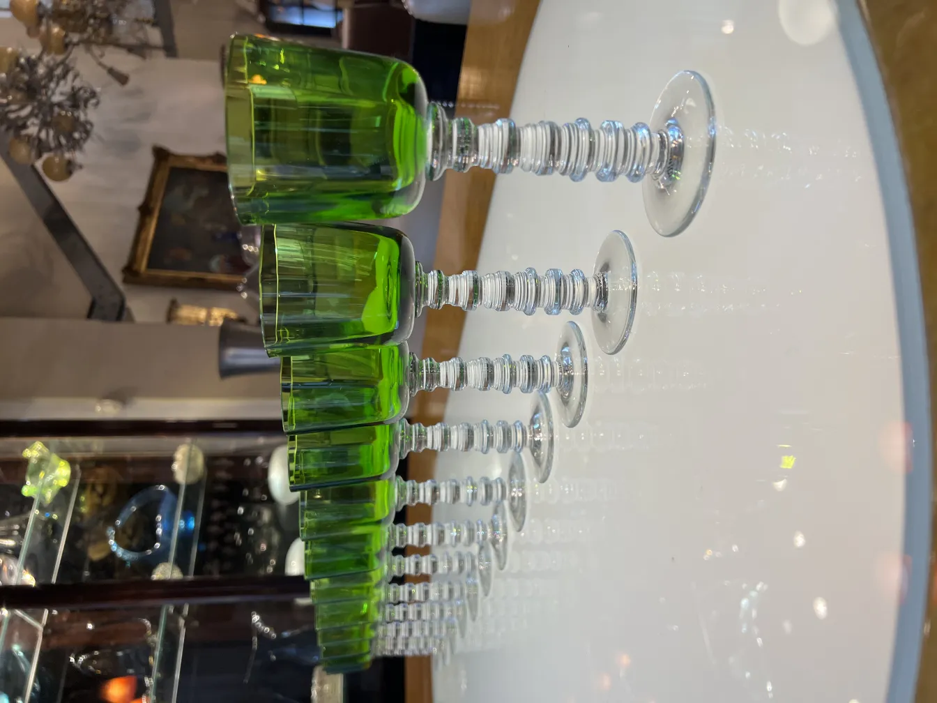Twelve green glasses Querandi arranged on a clear surface.