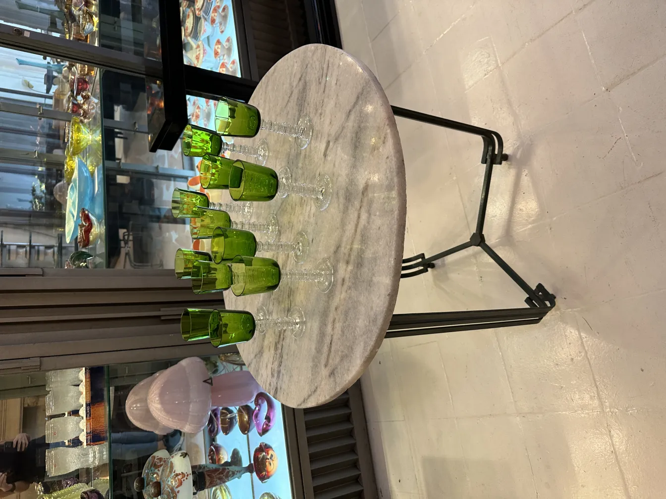 Set di 12 bicchieri querandi esposto in un ambiente antico, con una vetrina sullo sfondo