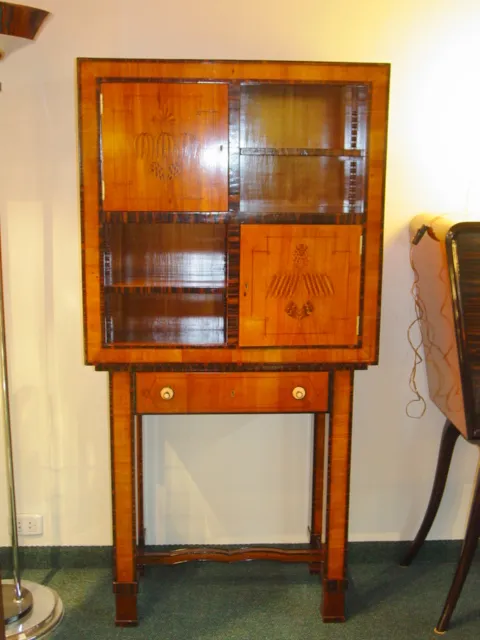 Mueble de habanos antiguo con detalles en varios paneles y un cajón inferior.