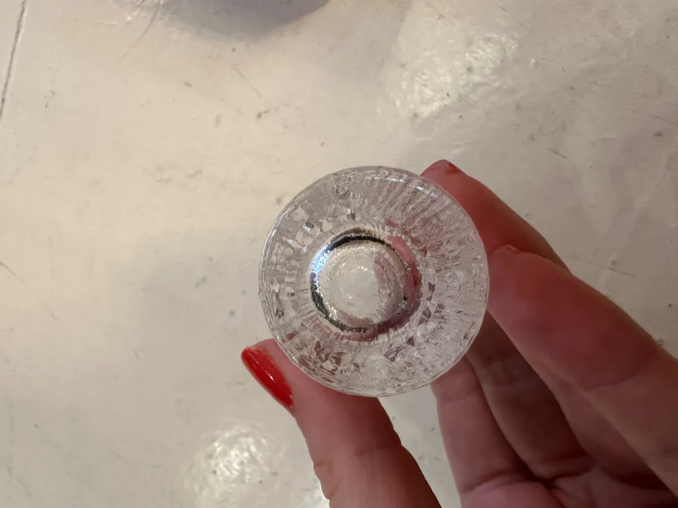 Vue de dessus de 6 verres anciens de Tapio Wirkkala tenus dans une main, sur un fond clair.