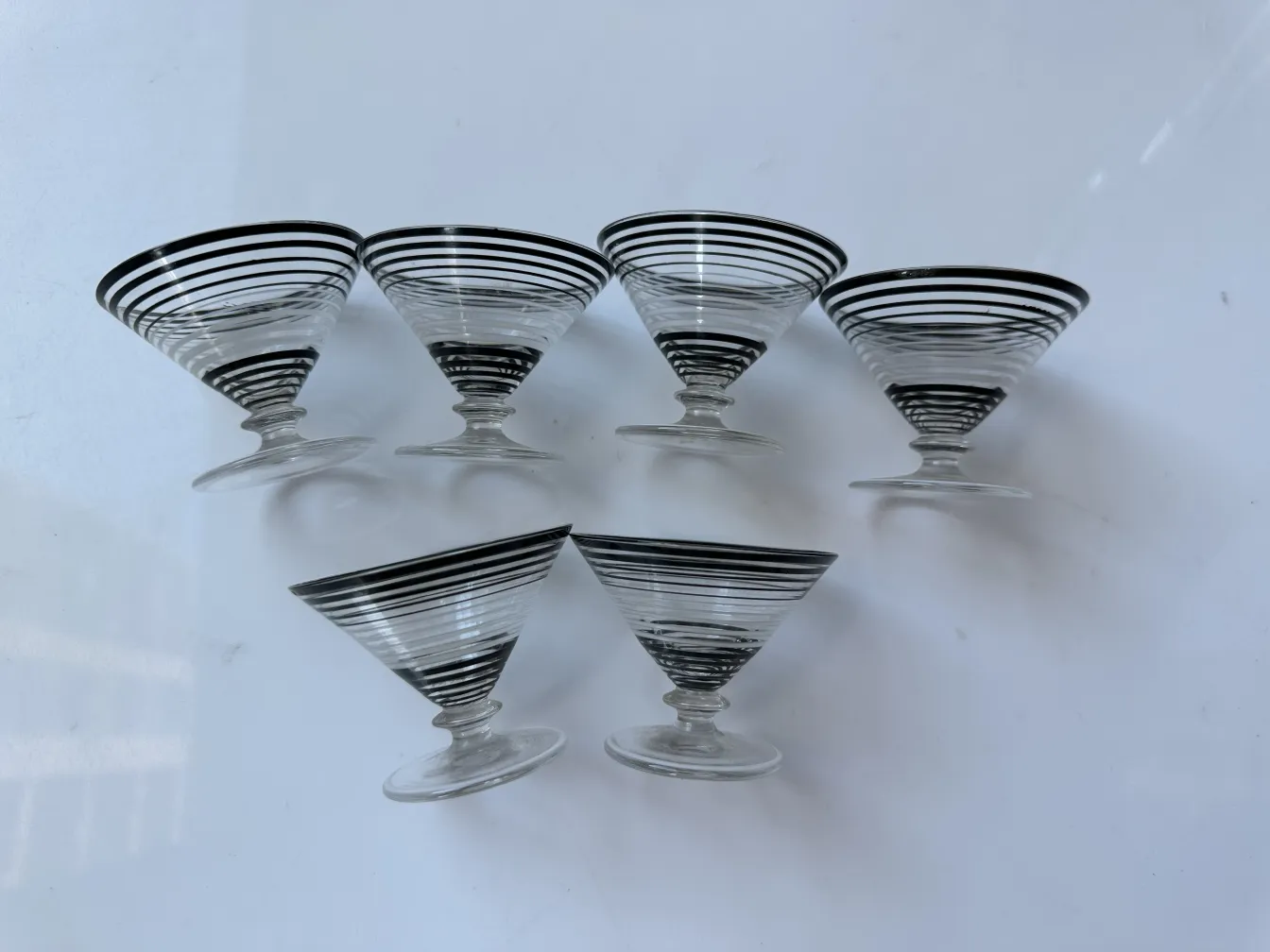 Set di liquore antico con 6 bicchieri decorati con strisce bianche e nere su sfondo bianco.