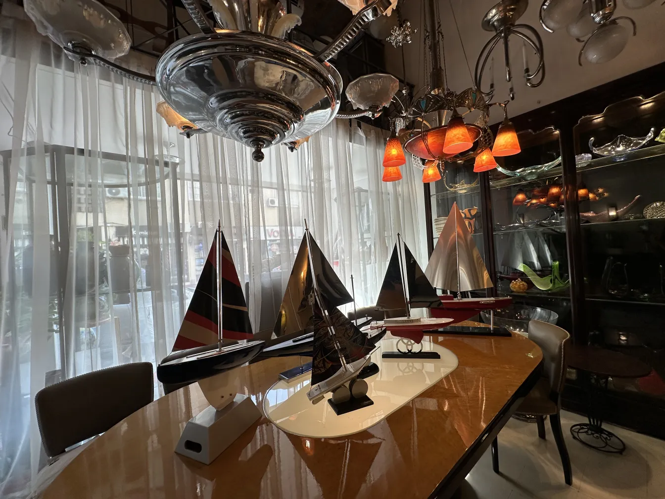 Modelo de barco antigo do designer Marcelo Peña em uma sala iluminada com itens decorativos.