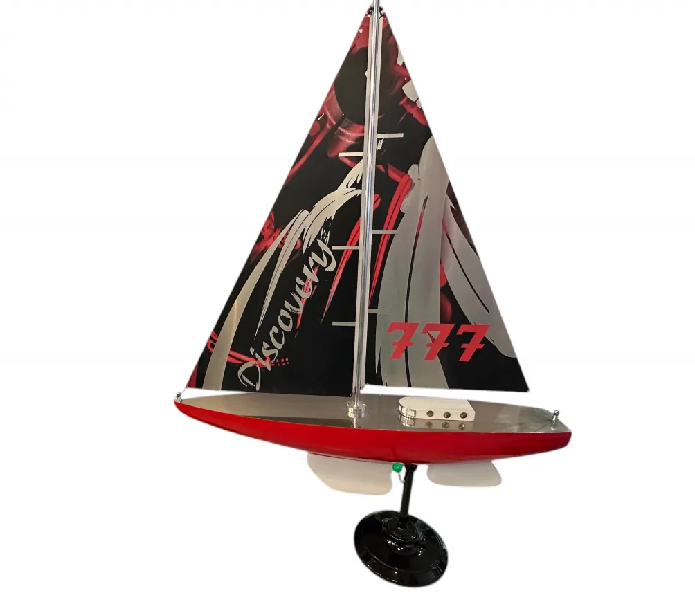 Modello antico della barca del designer Marcelo Peña, rosso e nero, con vela decorativa.