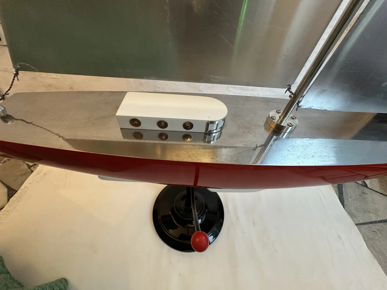 Modelo antigo de um barco do designer com acabamento vermelho e detalhes sofisticados, apresentado em um ambiente neutro.