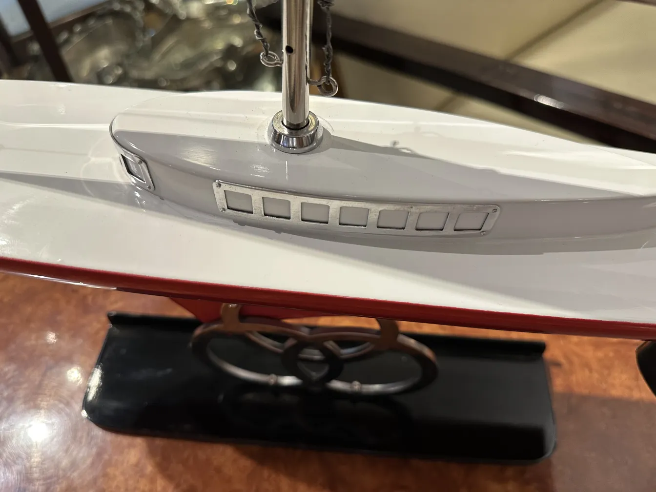 Scale model of an antique ship by designer Marcelo Peña, featuring visible details like windows and a shiny red and white finish.