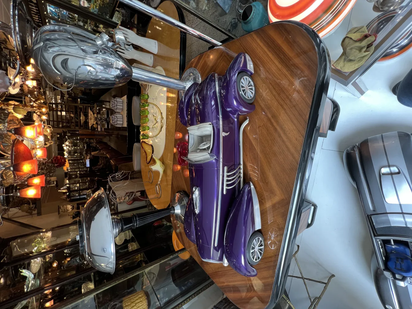 Ancient designer car by Marcelo Peña, purple, displayed among antiques