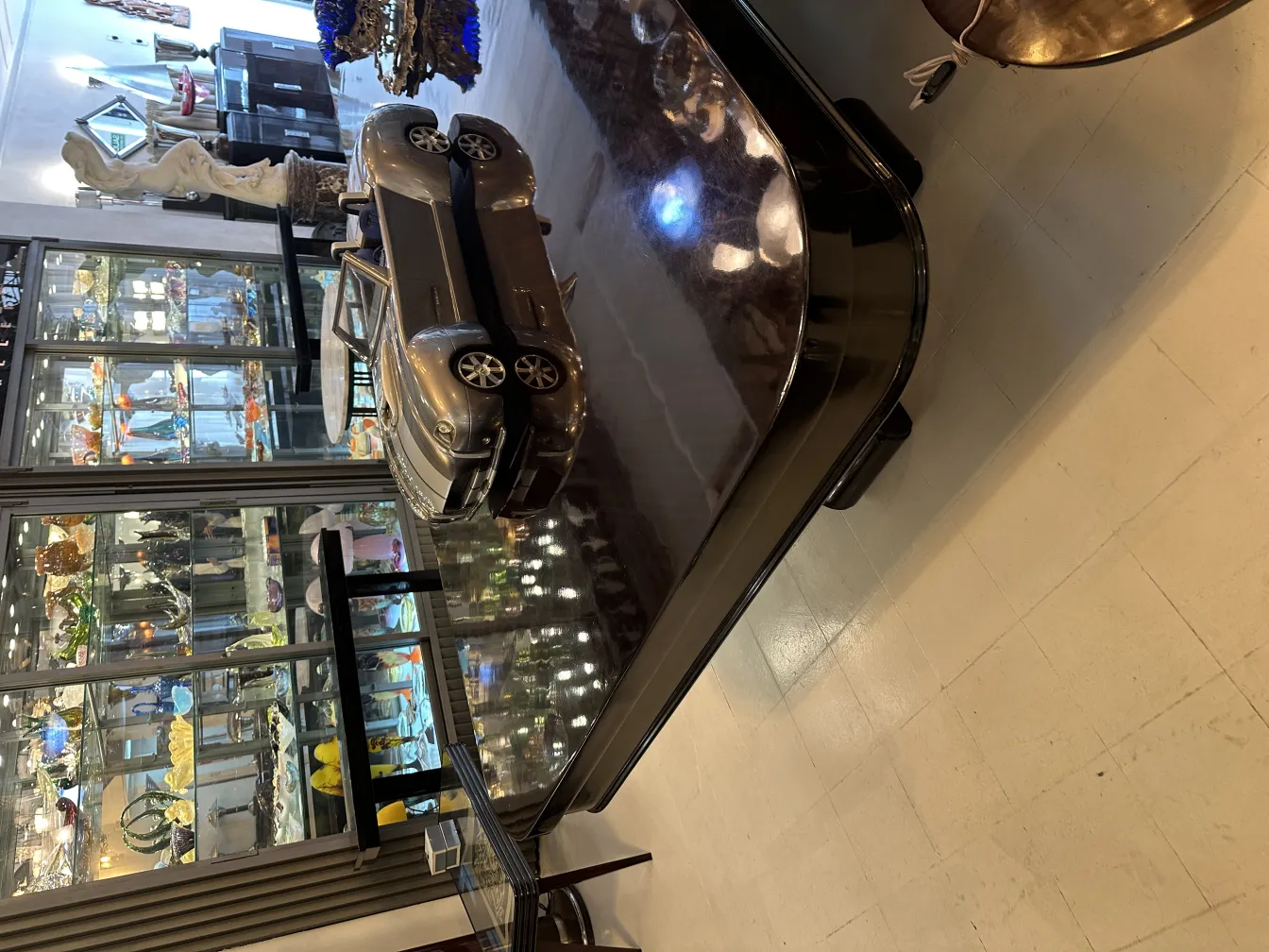 Auto del diseñador Marcelo Peña en una exhibición elegante, expuesto junto a antigüedades.