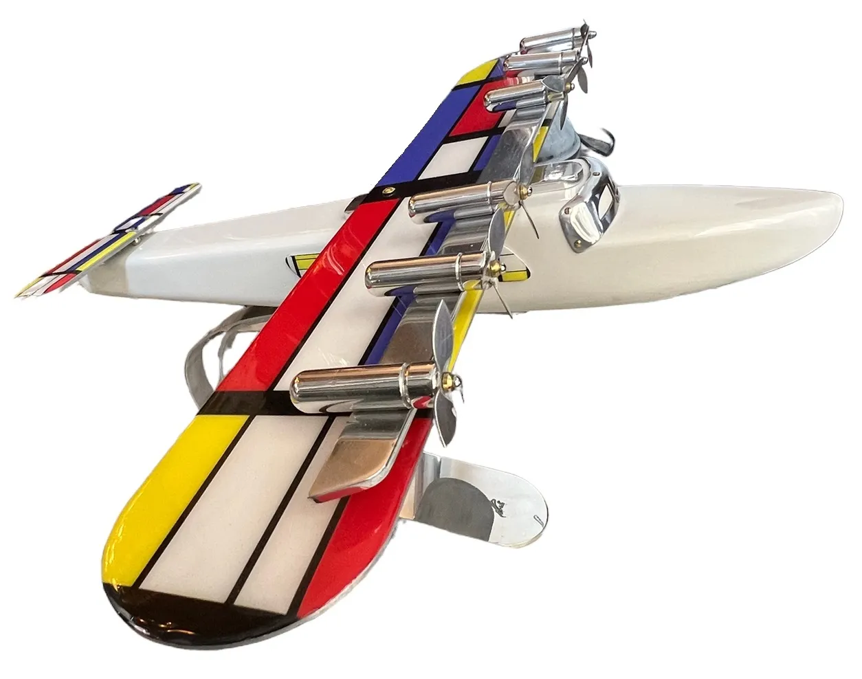 Modelo colorido de aviões antigos do designer Marcelo Peña, apresentando formas distintas em vermelho, amarelo e azul.