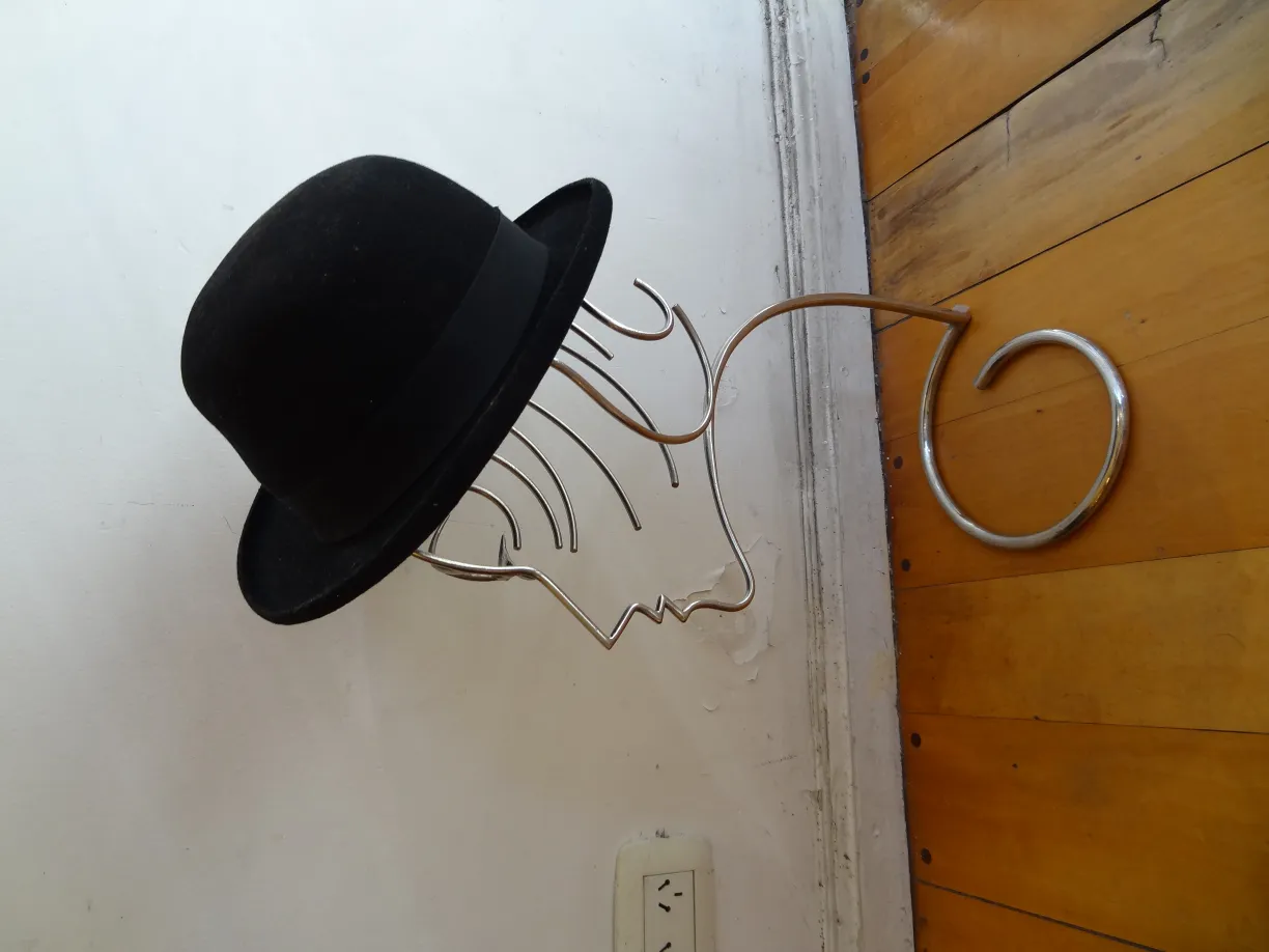 scultura antica con volto e cappello nero sulla parete