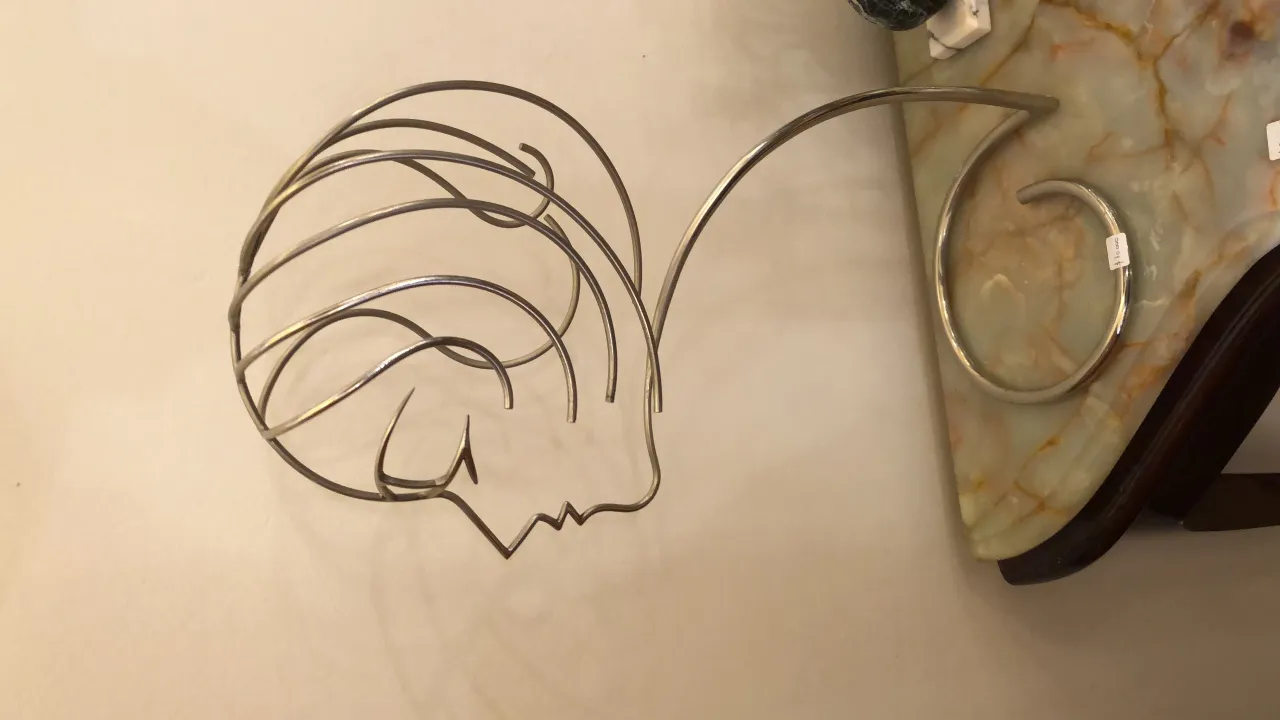 escultura antiga com um rosto estilizado e linhas fluidas