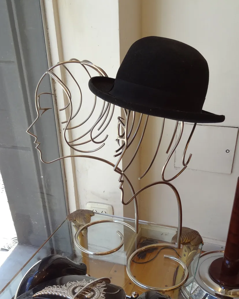 alte Skulptur mit Kopf-Silhouetten und schwarzem Hut