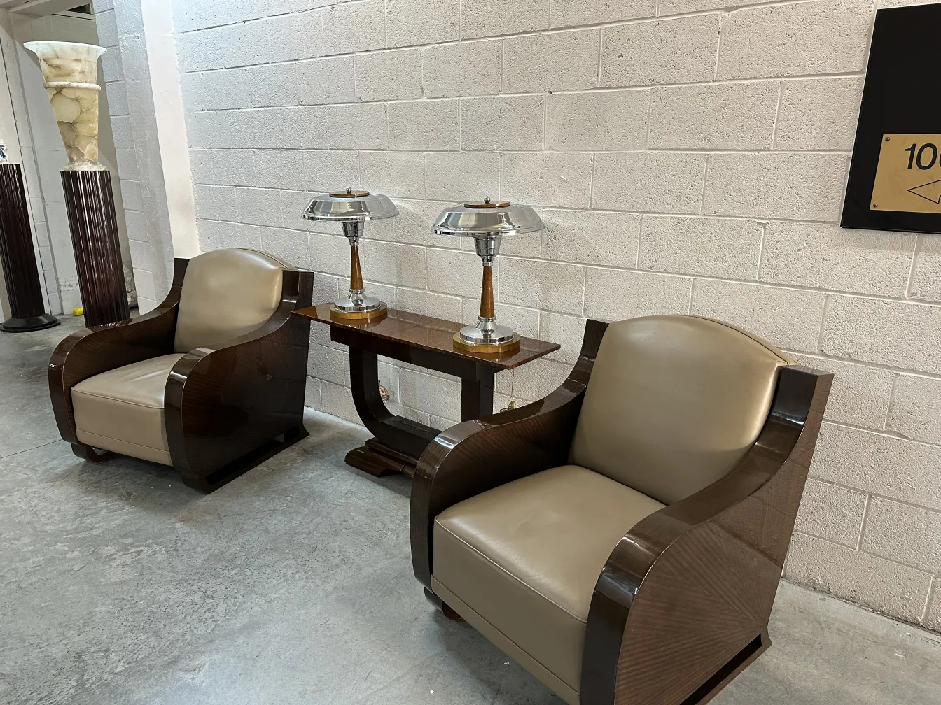 Ancienne console dans un cadre décoratif avec des fauteuils et des lampes.